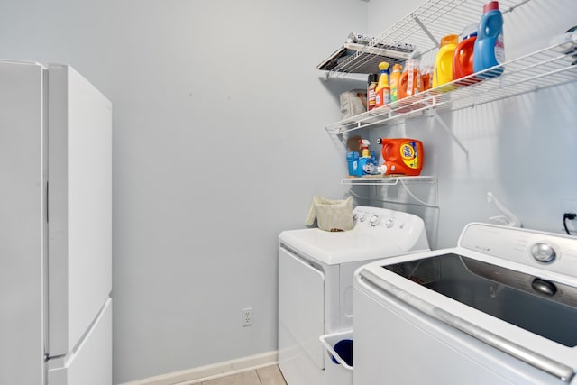 washroom with laundry area, light tile patterned flooring, washer and clothes dryer, and baseboards