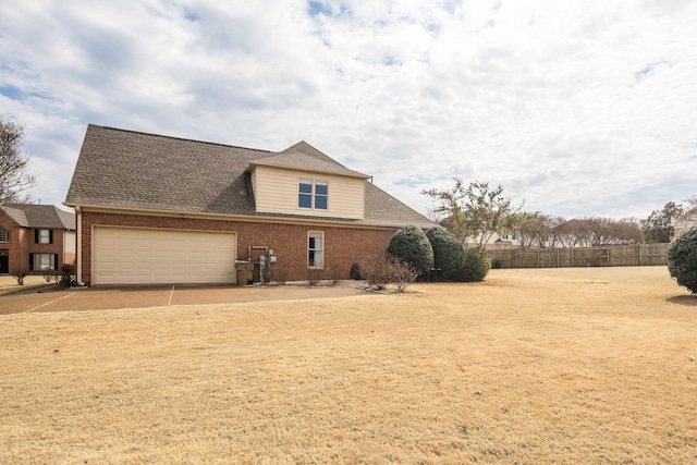 view of home's exterior with brick siding, roof with shingles, fence, a garage, and driveway