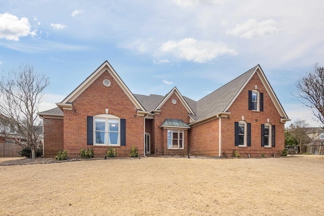 traditional-style house with brick siding, roof with shingles, and fence