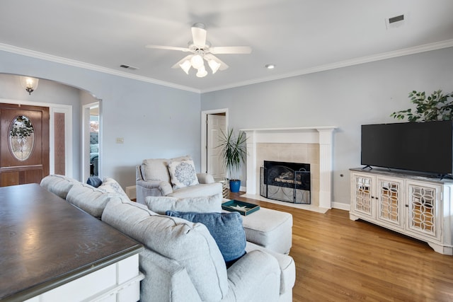 living area featuring arched walkways, visible vents, a fireplace, and wood finished floors