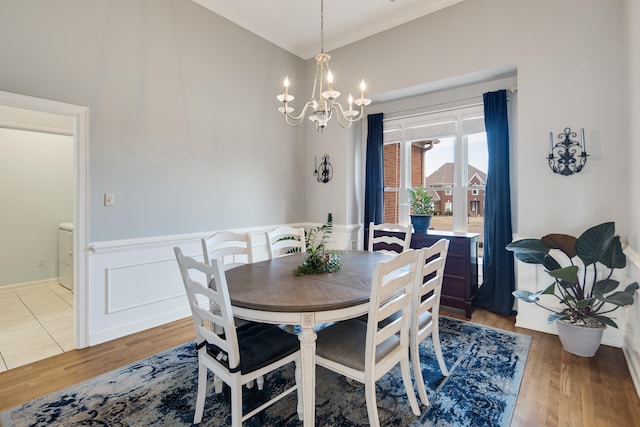 dining space featuring ornamental molding, wainscoting, wood finished floors, and a notable chandelier