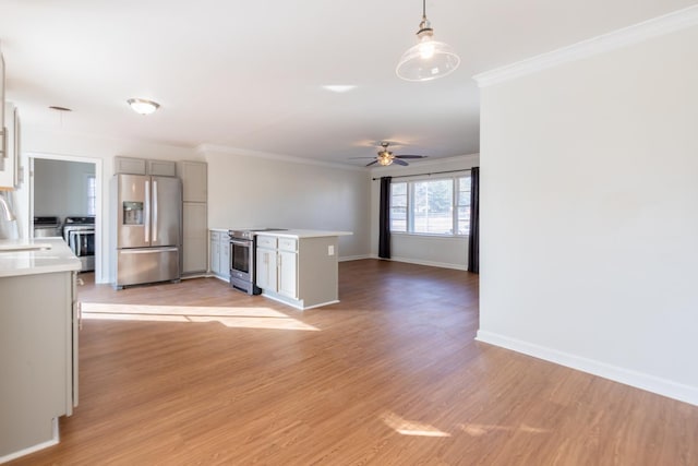 kitchen with ornamental molding, gray cabinets, stainless steel appliances, light countertops, and light wood-style floors