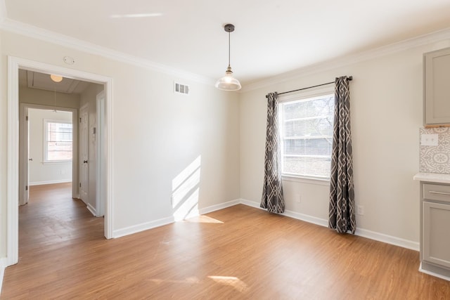 unfurnished dining area with visible vents, baseboards, ornamental molding, light wood finished floors, and attic access