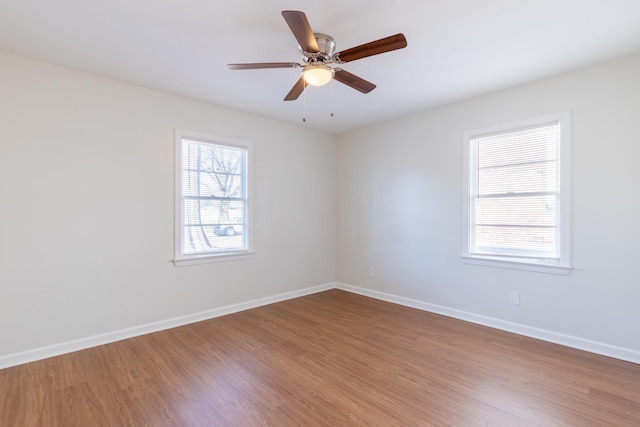 spare room featuring wood finished floors, a ceiling fan, and baseboards