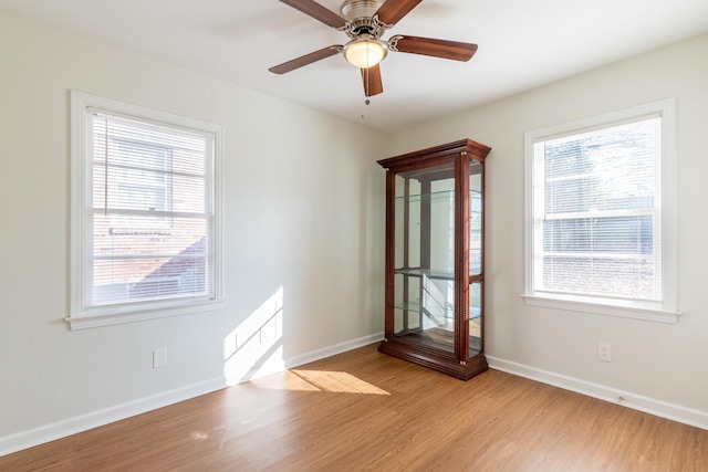 unfurnished room featuring a ceiling fan, light wood-type flooring, and baseboards