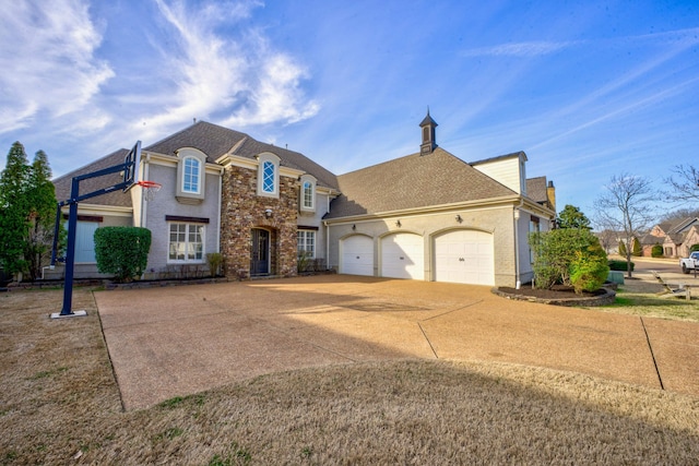 french country style house featuring a garage, concrete driveway, and a shingled roof