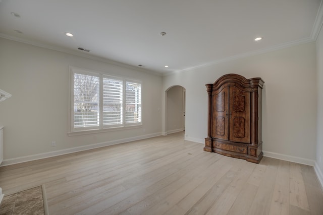 unfurnished living room featuring light wood finished floors, visible vents, arched walkways, and ornamental molding