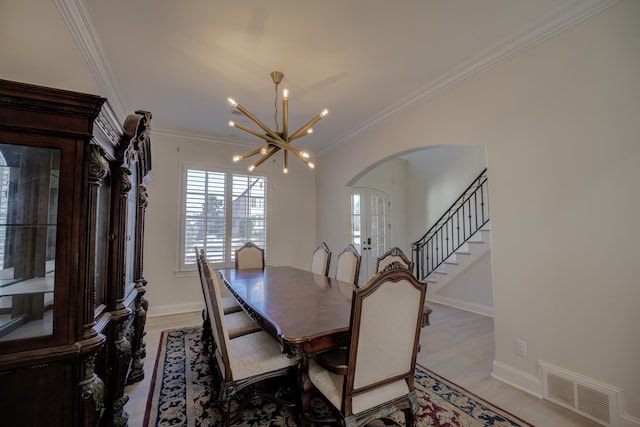 dining space with arched walkways, crown molding, a notable chandelier, visible vents, and light wood-style floors