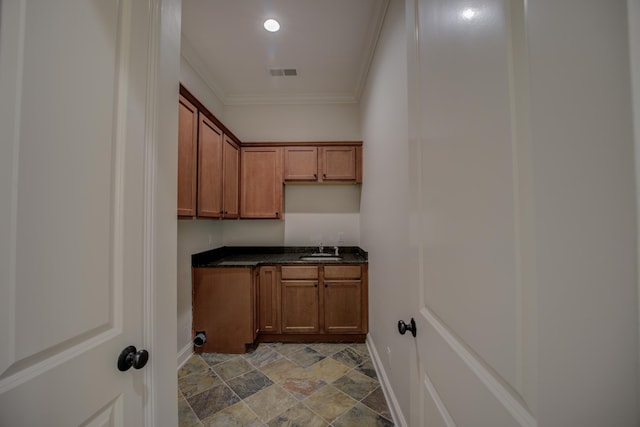 laundry room with a sink, visible vents, baseboards, ornamental molding, and stone finish floor