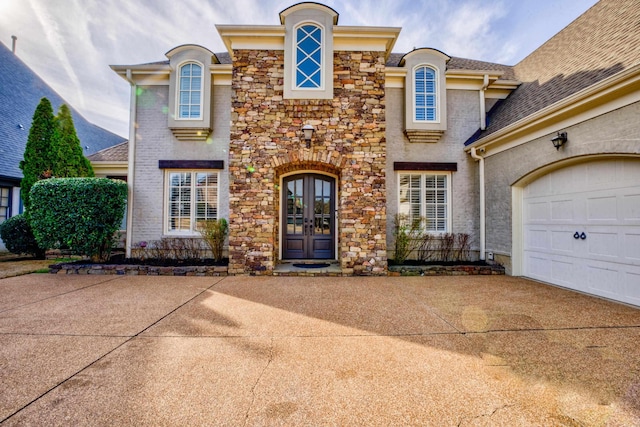 view of front facade with stone siding, french doors, and driveway