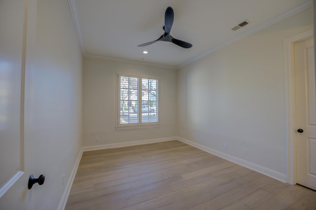 spare room featuring baseboards, light wood-style flooring, visible vents, and crown molding