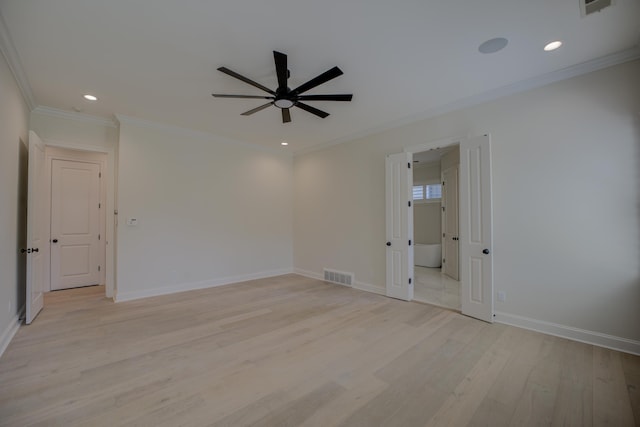 spare room with light wood finished floors, baseboards, visible vents, and crown molding