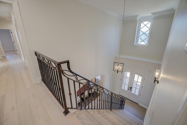 foyer entrance featuring wood finished floors, baseboards, ornamental molding, french doors, and an inviting chandelier