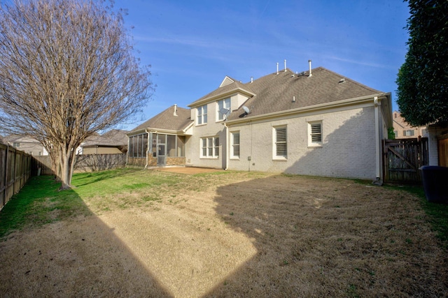 rear view of property featuring brick siding, a yard, a sunroom, a patio area, and a fenced backyard