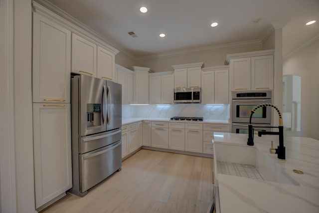 kitchen featuring light wood-style flooring, decorative backsplash, appliances with stainless steel finishes, ornamental molding, and white cabinets