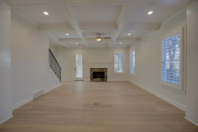 unfurnished living room with beam ceiling, visible vents, light wood-style floors, coffered ceiling, and stairs