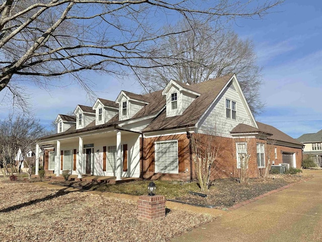 view of front facade with central air condition unit, a porch, and brick siding