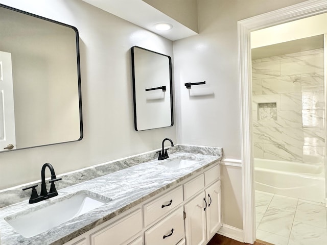 bathroom featuring marble finish floor, double vanity, a sink, and shower / bathing tub combination