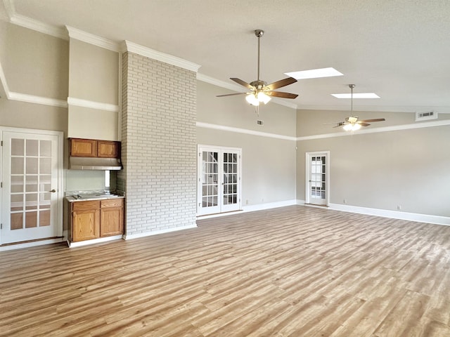 unfurnished living room featuring ceiling fan, light wood-type flooring, ornamental molding, and a skylight