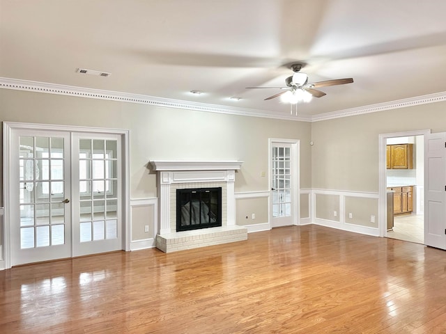 unfurnished living room featuring crown molding, a fireplace, visible vents, and wood finished floors