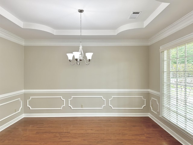 unfurnished dining area featuring wood finished floors, visible vents, a tray ceiling, an inviting chandelier, and crown molding