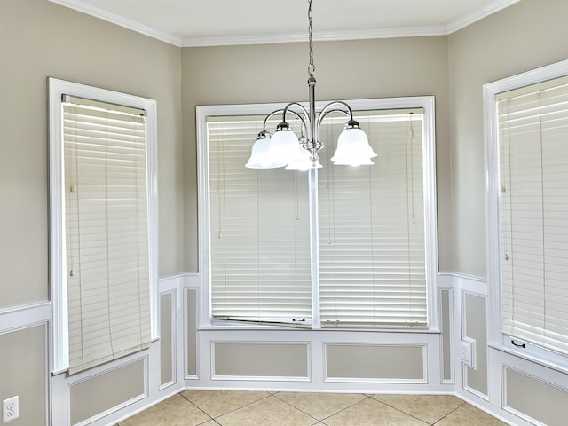 unfurnished dining area with a wainscoted wall, crown molding, a chandelier, a decorative wall, and light tile patterned flooring