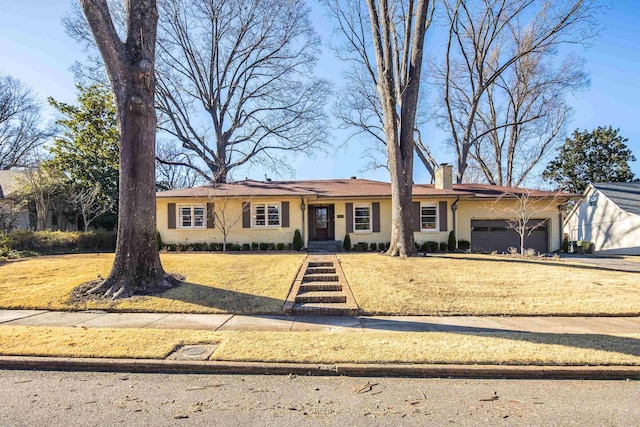 ranch-style home with an attached garage, a chimney, a front lawn, and brick siding