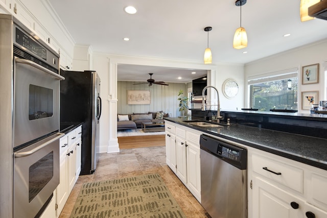 kitchen with appliances with stainless steel finishes, a sink, white cabinets, and crown molding