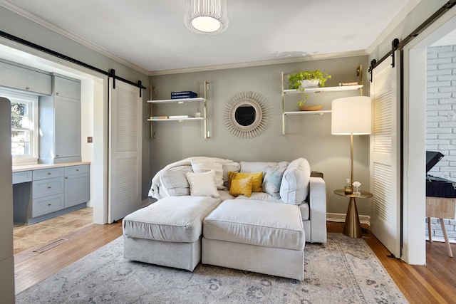 living area with ornamental molding, a barn door, and light wood-style floors