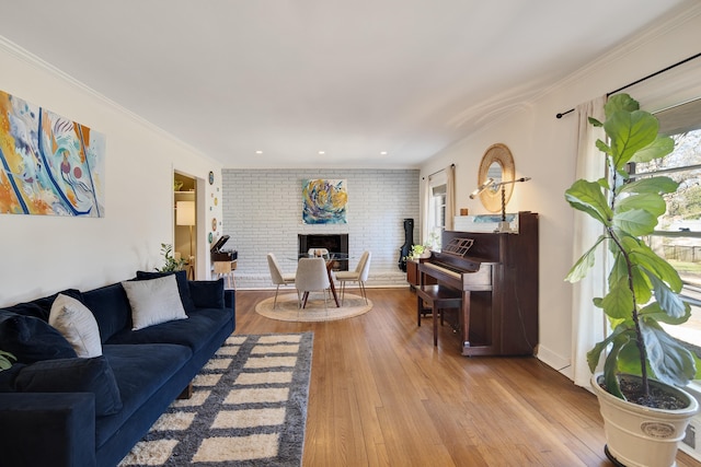 living room featuring ornamental molding, a fireplace, brick wall, and wood finished floors