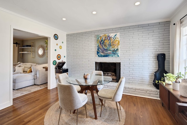 dining space featuring brick wall, ornamental molding, and wood finished floors