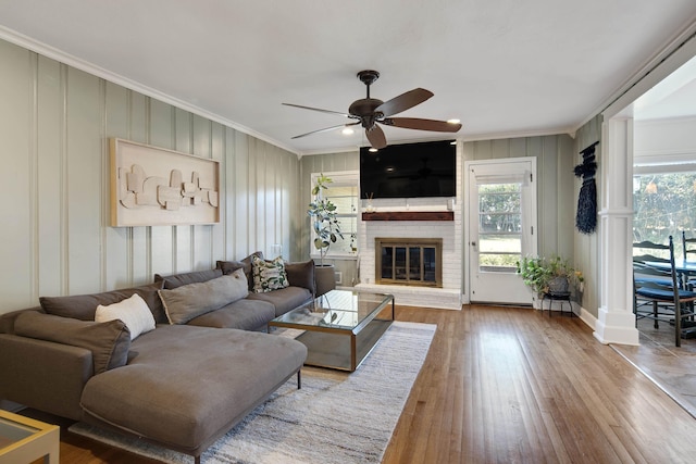 living area featuring a wealth of natural light, a fireplace, crown molding, and wood finished floors