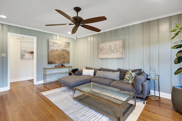 living area with baseboards, ornamental molding, and wood finished floors