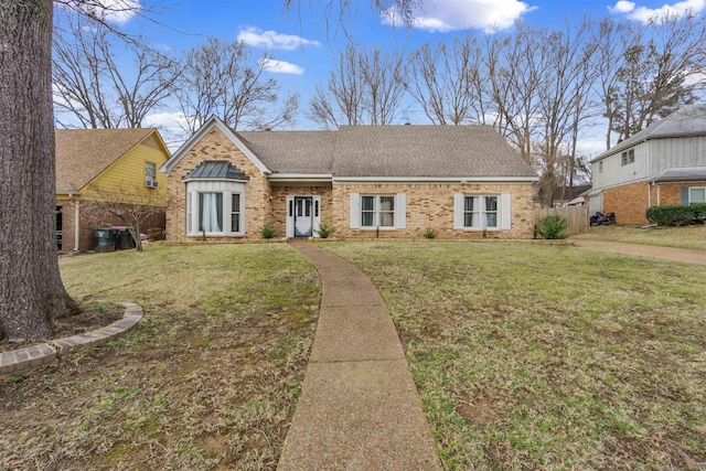 view of front of house featuring roof with shingles, brick siding, and a front lawn