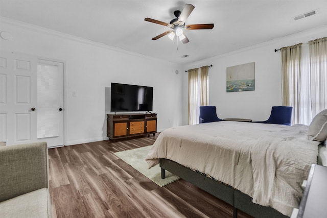 bedroom with ornamental molding, multiple windows, wood finished floors, and visible vents