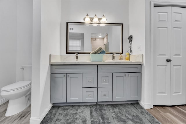 bathroom featuring double vanity, baseboards, toilet, walk in shower, and a sink