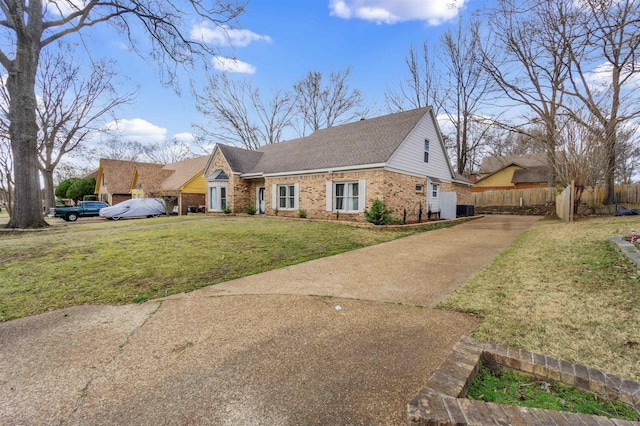 view of front of property with a shingled roof, fence, a front lawn, and brick siding