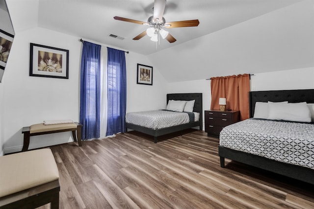 bedroom featuring vaulted ceiling, wood finished floors, visible vents, and a ceiling fan