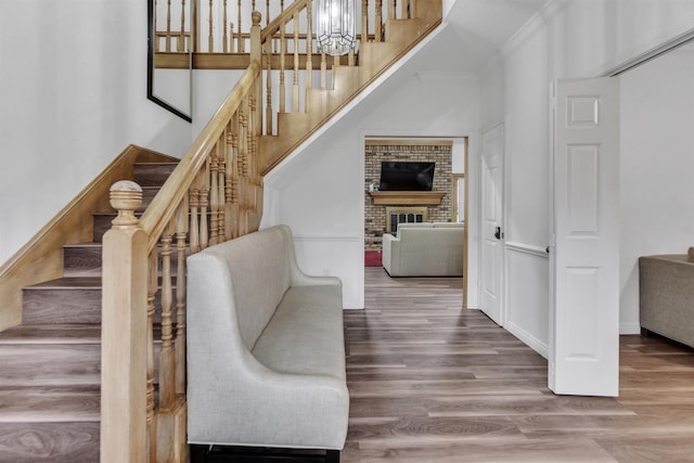 staircase with crown molding, a fireplace, and wood finished floors