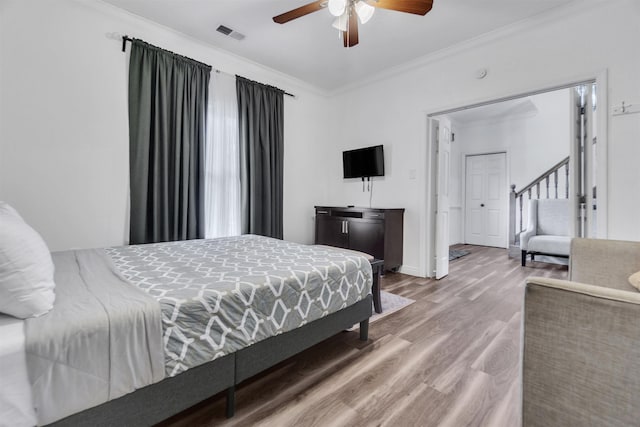 bedroom featuring ceiling fan, ornamental molding, wood finished floors, and visible vents