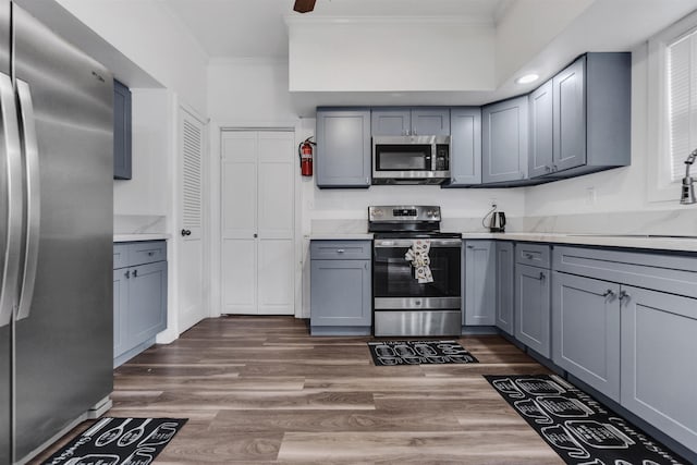 kitchen with crown molding, stainless steel appliances, dark wood finished floors, and gray cabinetry