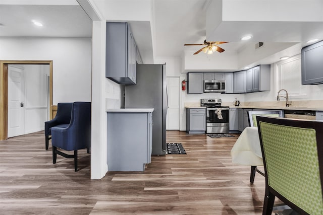 kitchen with gray cabinets, light countertops, light wood-style flooring, appliances with stainless steel finishes, and ceiling fan