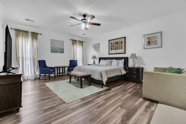 bedroom featuring a ceiling fan, dark wood-style flooring, visible vents, and crown molding