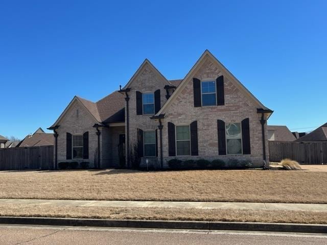 view of front of home with brick siding and fence