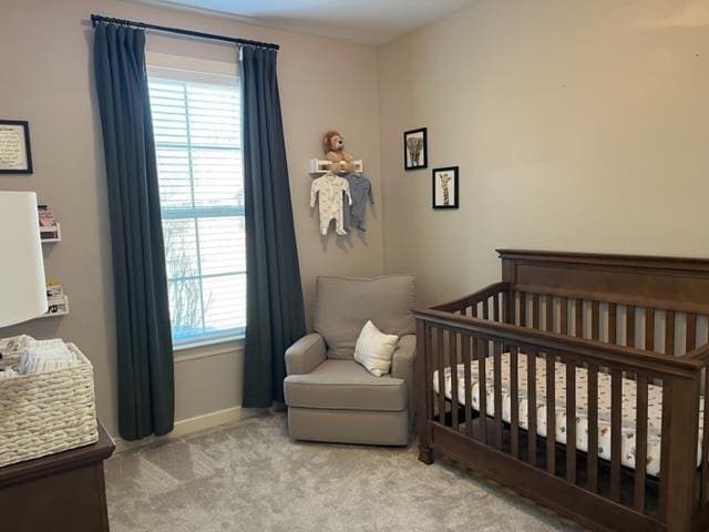 carpeted bedroom featuring a nursery area and baseboards