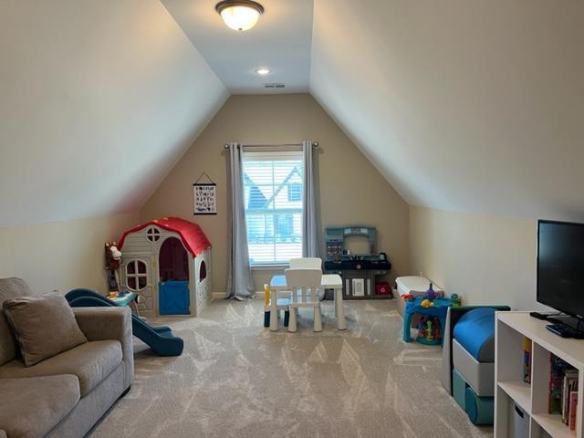 rec room with vaulted ceiling, carpet flooring, and visible vents