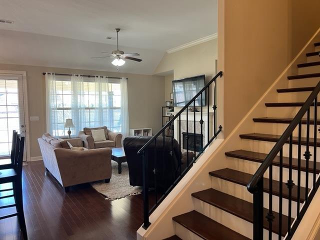 living area featuring stairs, a wealth of natural light, ceiling fan, and wood finished floors