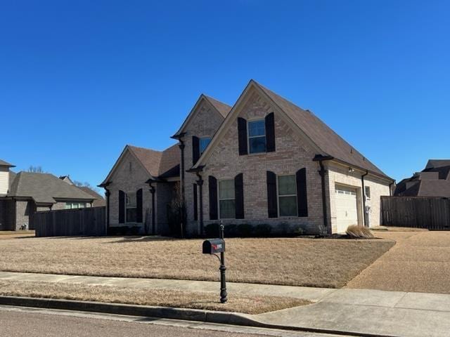 view of front of home featuring brick siding, fence, driveway, and an attached garage