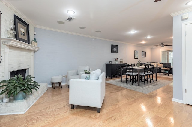 living area featuring light wood-style flooring, a fireplace, and ornamental molding