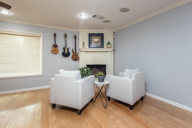 living area with light wood-style flooring, a fireplace, visible vents, baseboards, and ornamental molding